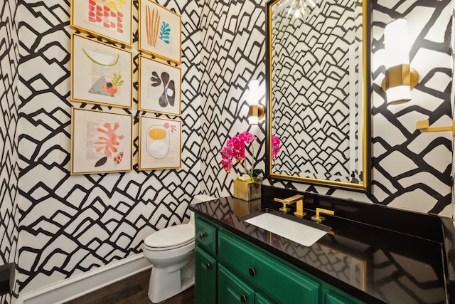 bathroom with vanity, wood finished floors, toilet, and wallpapered walls