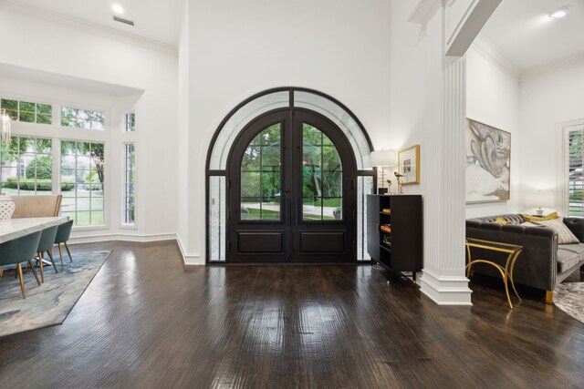 foyer featuring wood-type flooring, arched walkways, a high ceiling, and ornamental molding
