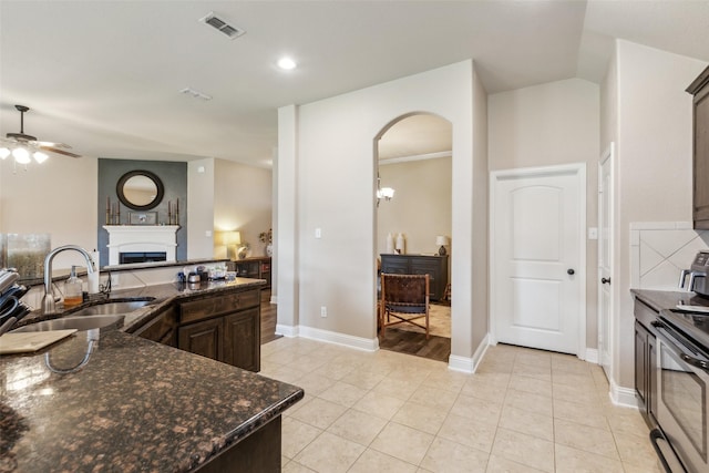 kitchen featuring electric range, ceiling fan, a fireplace, a sink, and visible vents