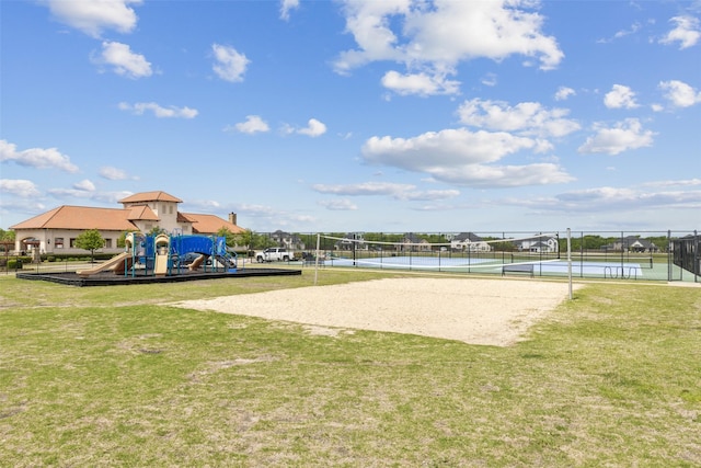 view of property's community featuring fence, a tennis court, volleyball court, a lawn, and playground community