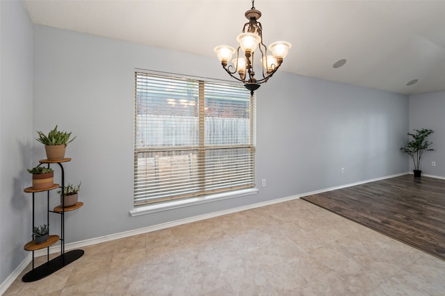 empty room featuring a chandelier and baseboards