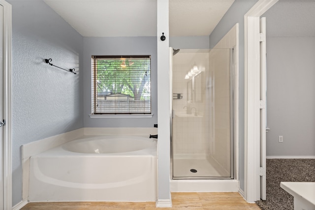 full bathroom with baseboards, wood finished floors, a shower stall, and a garden tub