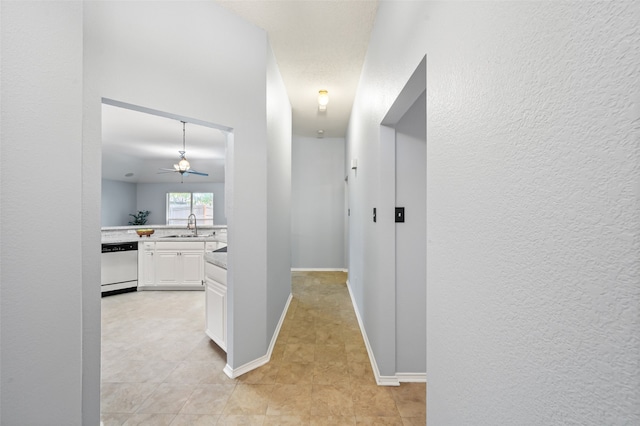 hallway with baseboards, light tile patterned flooring, and a sink