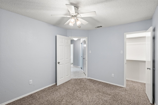 unfurnished bedroom featuring a textured ceiling, visible vents, a spacious closet, and carpet floors