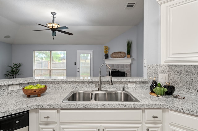 kitchen featuring a sink, a ceiling fan, dishwashing machine, visible vents, and lofted ceiling