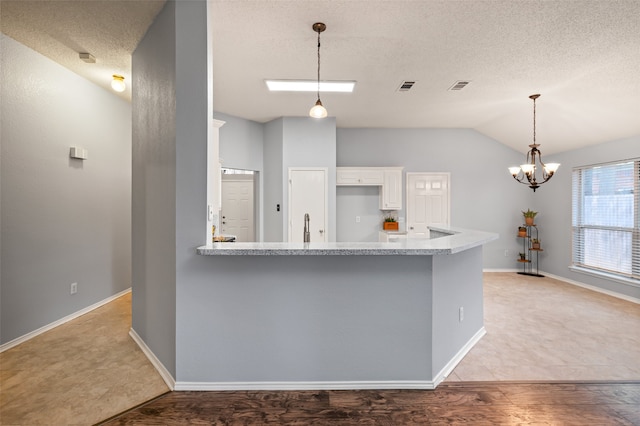 kitchen featuring lofted ceiling, white cabinets, visible vents, a peninsula, and a notable chandelier