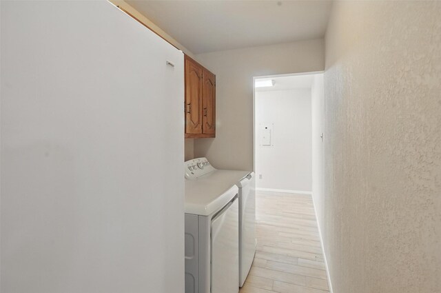 laundry room with washer and dryer, cabinet space, and light wood finished floors