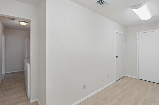 interior space with baseboards, visible vents, light wood-style floors, and washing machine and dryer