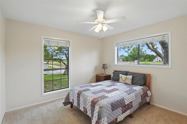 carpeted bedroom with ceiling fan and baseboards