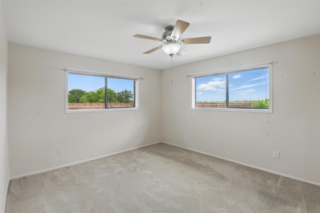 unfurnished room featuring a wealth of natural light, ceiling fan, baseboards, and light carpet