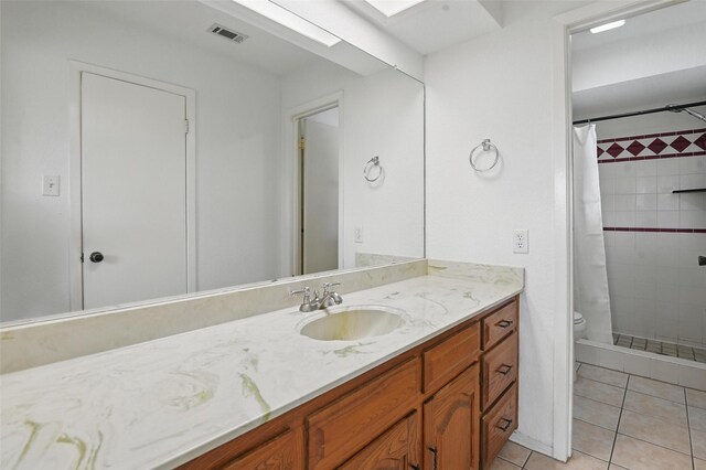 full bathroom with a tile shower, tile patterned floors, toilet, vanity, and visible vents