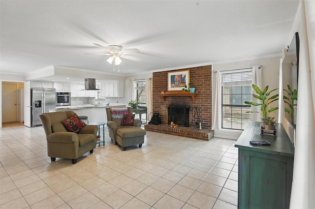 living area featuring crown molding, a ceiling fan, light tile patterned floors, and a brick fireplace