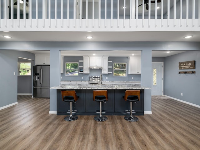 kitchen with white cabinetry, appliances with stainless steel finishes, wood finished floors, and baseboards