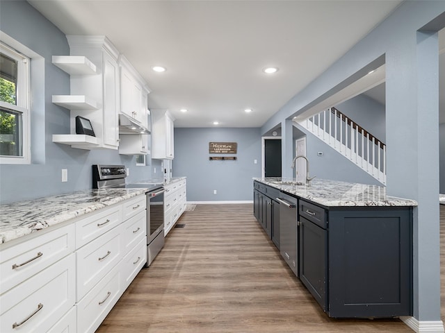 kitchen with a sink, open shelves, light wood-type flooring, white cabinetry, and appliances with stainless steel finishes