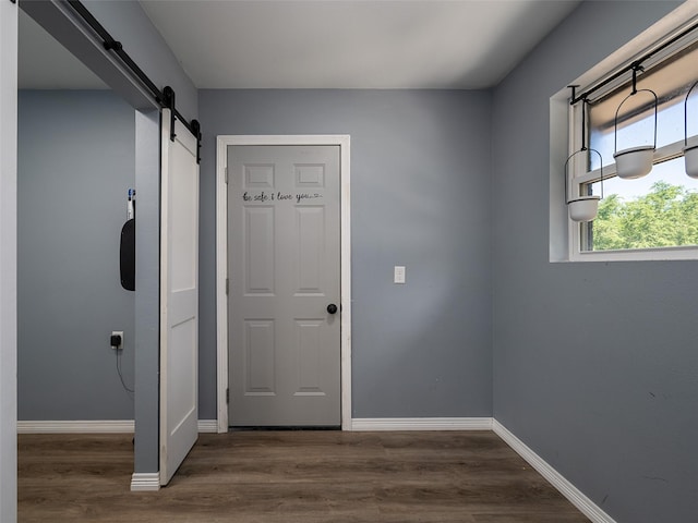 doorway featuring baseboards, a barn door, and wood finished floors
