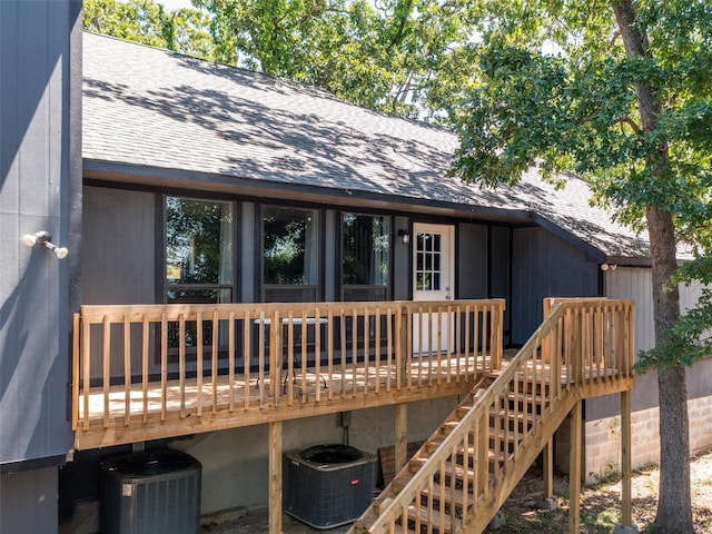 back of house featuring a deck, central air condition unit, and roof with shingles