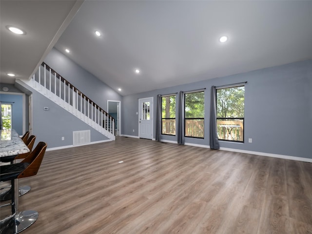 unfurnished living room featuring baseboards, stairway, and plenty of natural light