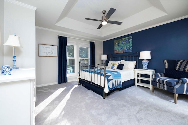 bedroom featuring carpet flooring, ceiling fan, a tray ceiling, baseboards, and ornamental molding
