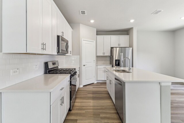kitchen featuring wood finished floors, appliances with stainless steel finishes, light countertops, and a sink