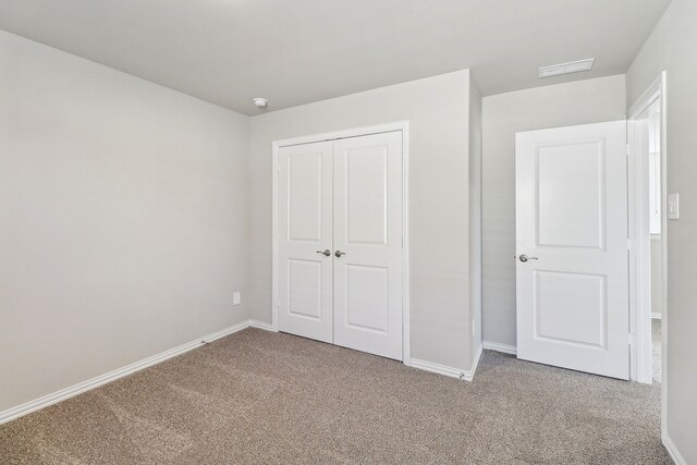 unfurnished bedroom featuring a closet, carpet flooring, visible vents, and baseboards