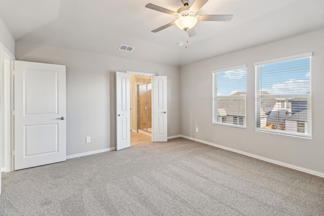 unfurnished bedroom with connected bathroom, light colored carpet, vaulted ceiling, baseboards, and visible vents