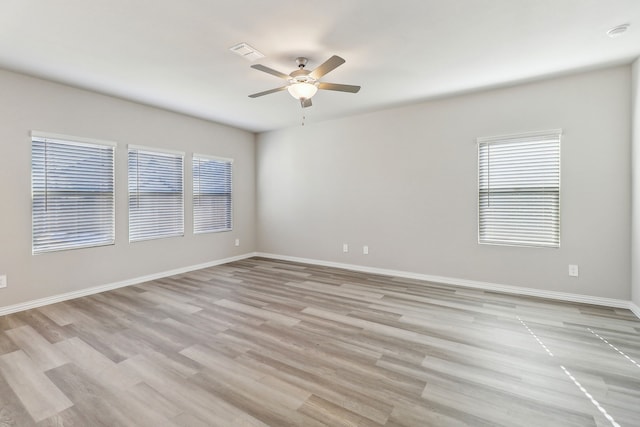 unfurnished room with light wood finished floors, ceiling fan, a healthy amount of sunlight, and visible vents