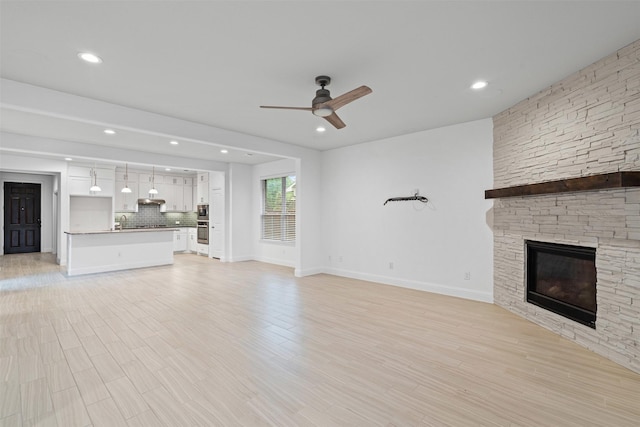 unfurnished living room featuring recessed lighting, a fireplace, a sink, baseboards, and a ceiling fan
