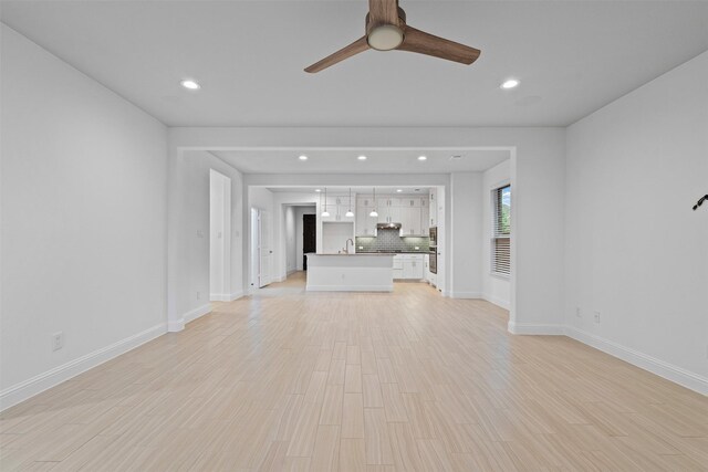 unfurnished living room with a sink, ceiling fan, light wood-style floors, baseboards, and recessed lighting