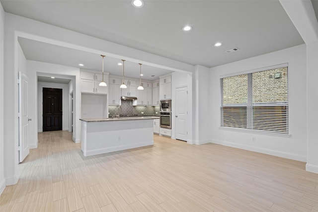 kitchen with white cabinetry, stainless steel appliances, backsplash, baseboards, and open floor plan