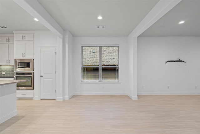 kitchen with white cabinetry, stainless steel appliances, backsplash, baseboards, and open floor plan