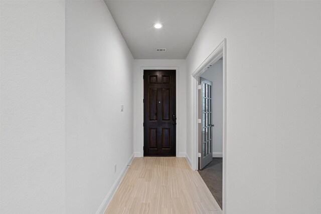 corridor featuring light wood finished floors, recessed lighting, visible vents, and baseboards