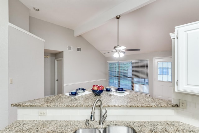 kitchen with a sink, ceiling fan, visible vents, light stone counters, and white cabinets