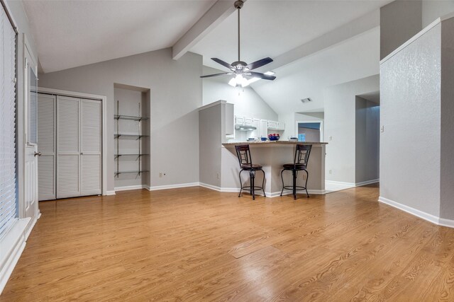 living room with ceiling fan, vaulted ceiling with beams, light wood-type flooring, visible vents, and baseboards