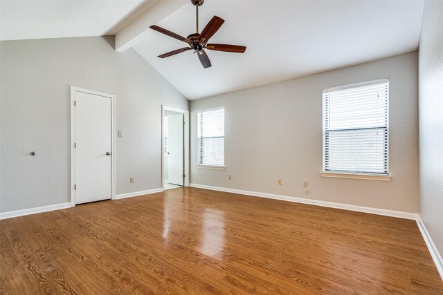 empty room featuring ceiling fan, vaulted ceiling with beams, wood finished floors, and baseboards