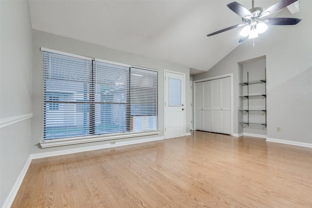 unfurnished living room with wood finished floors, ceiling fan, vaulted ceiling, and baseboards