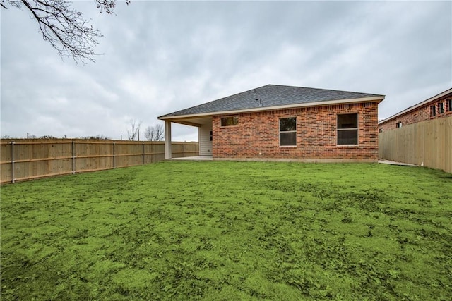 10121 Budtime Ln, Dallas, TX 75217 - rear view of house with a fenced backyard, a shingled roof, a lawn, and brick siding