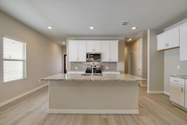 kitchen with tasteful backsplash, appliances with stainless steel finishes, light wood-style floors, visible vents, and baseboards