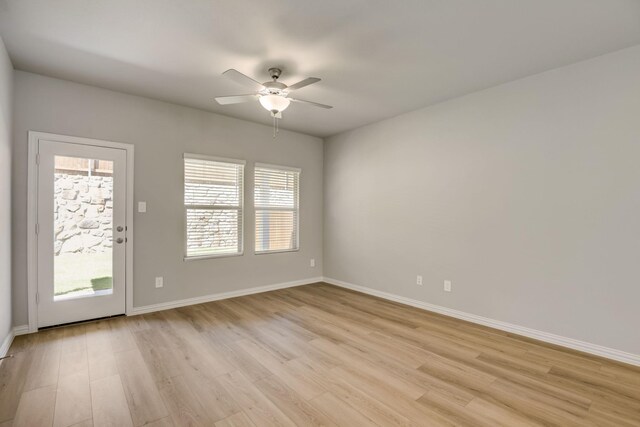 spare room with baseboards, ceiling fan, and light wood-style flooring