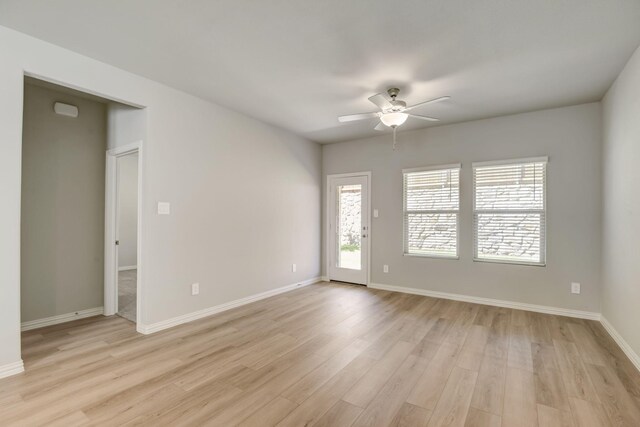 spare room featuring baseboards, light wood-type flooring, and a ceiling fan