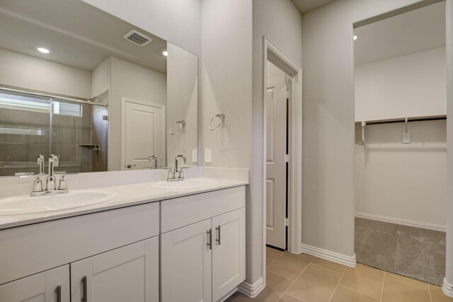 full bathroom featuring double vanity, a sink, a shower stall, and visible vents