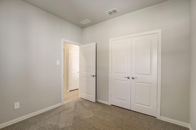 unfurnished bedroom with a closet, visible vents, light carpet, and baseboards