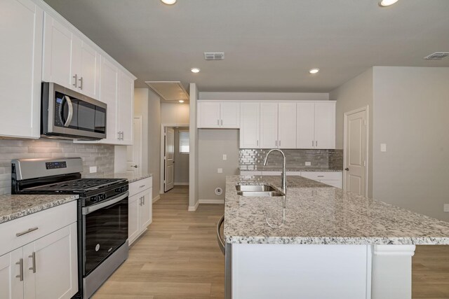 kitchen featuring appliances with stainless steel finishes, light wood-style floors, baseboards, and a sink