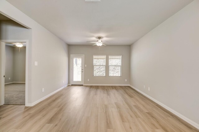 empty room with visible vents, a ceiling fan, light wood-style flooring, and baseboards
