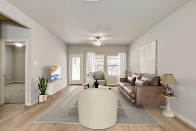 living area with visible vents, ceiling fan, light wood finished floors, and baseboards