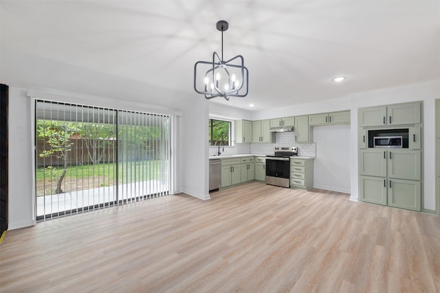 kitchen with green cabinetry, appliances with stainless steel finishes, light countertops, a sink, and a notable chandelier