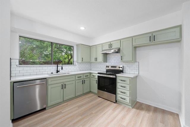 kitchen featuring appliances with stainless steel finishes, green cabinetry, light countertops, and a sink