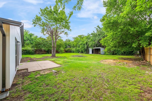 view of yard featuring an outbuilding, a storage unit, a fenced backyard, and a patio area