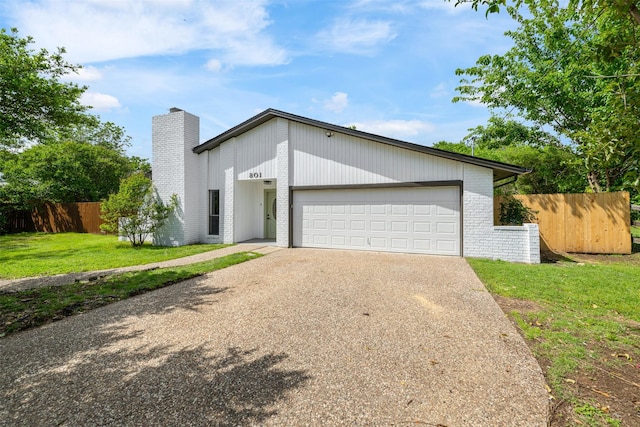 mid-century home with a chimney, fence, a garage, a front lawn, and concrete driveway