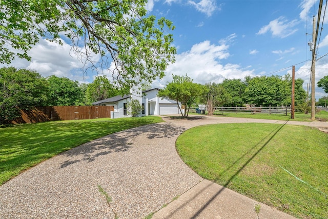 view of front facade featuring a garage, fence, a front lawn, and driveway