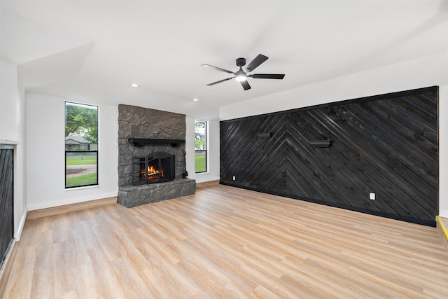 unfurnished living room featuring a ceiling fan, wood finished floors, a healthy amount of sunlight, and a fireplace